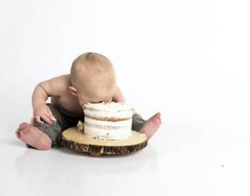 kid sitting beside round cake close-up photography