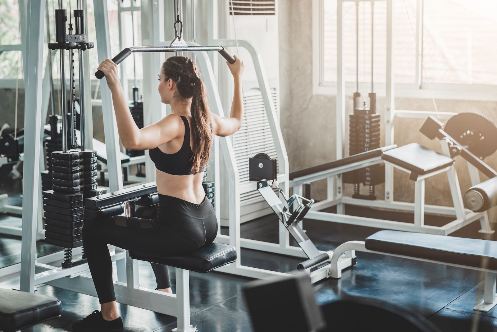 Fit young caucasian woman performing a  pull workout on a lat pulldown machine.