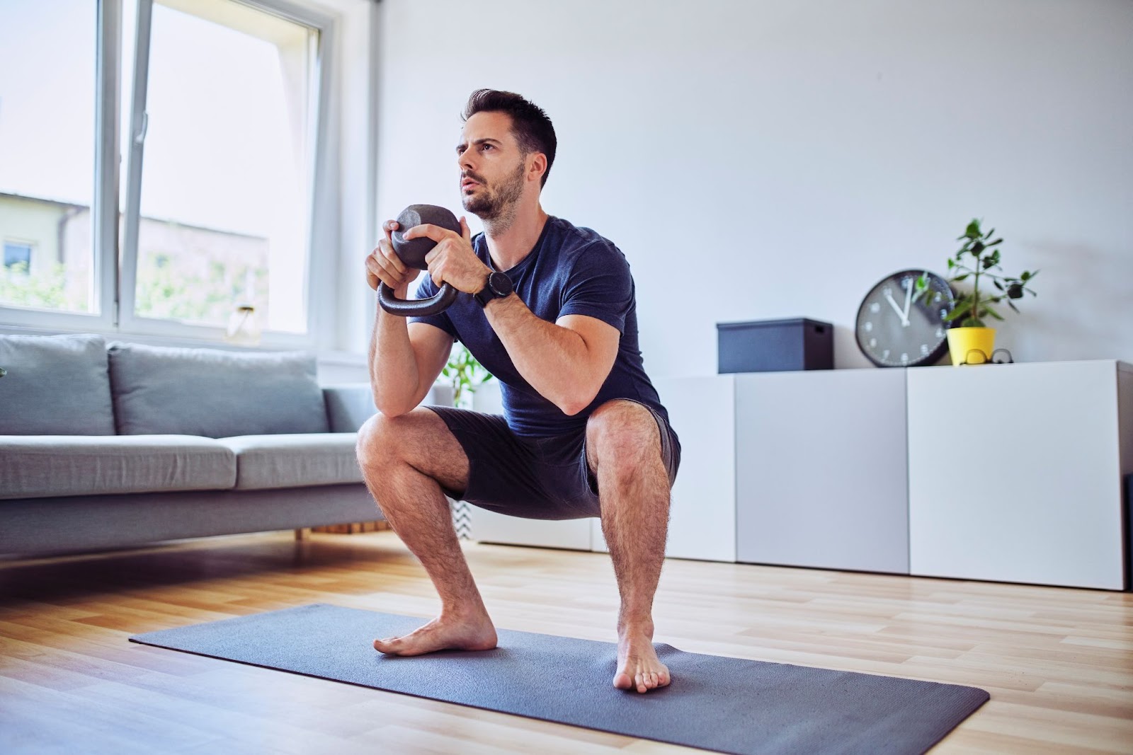 Man holding a kettlebell in the Goblet Squat position.