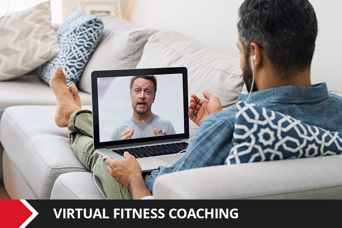 Man staring at his computer, having a virtual fitness coaching session with a trainer.