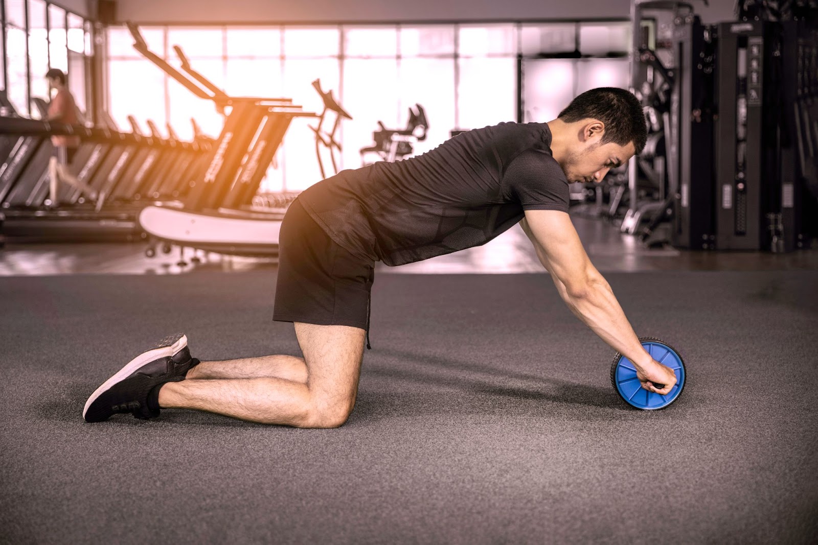 Young sporty gentleman doing ab wheel roller workout.