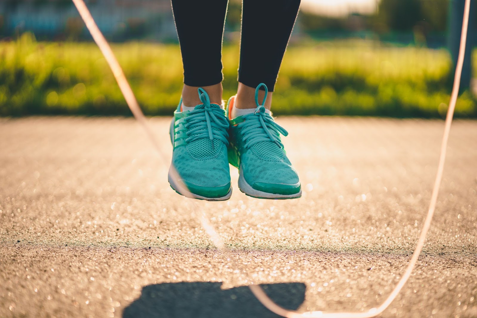 Closeup of woman in blue shoes jumping rope outside