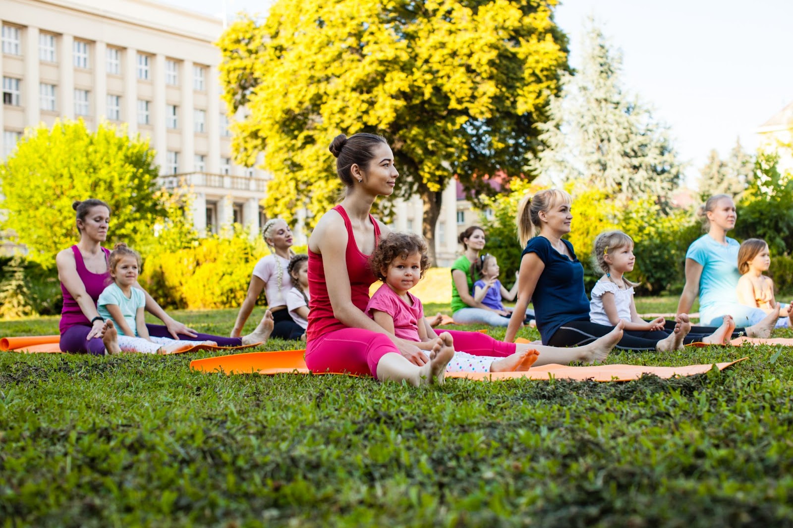 Group of young women taking a Mommy & Me yoga class in the park