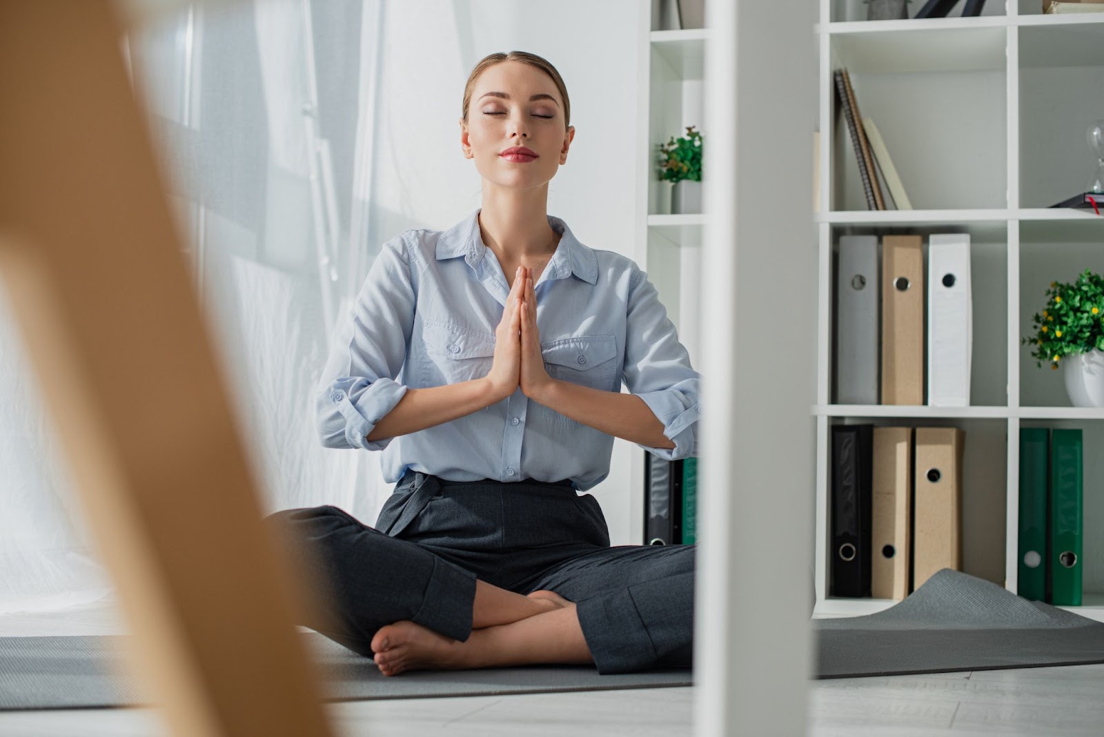 Professional young woman practicing yoga on a mat in her office.