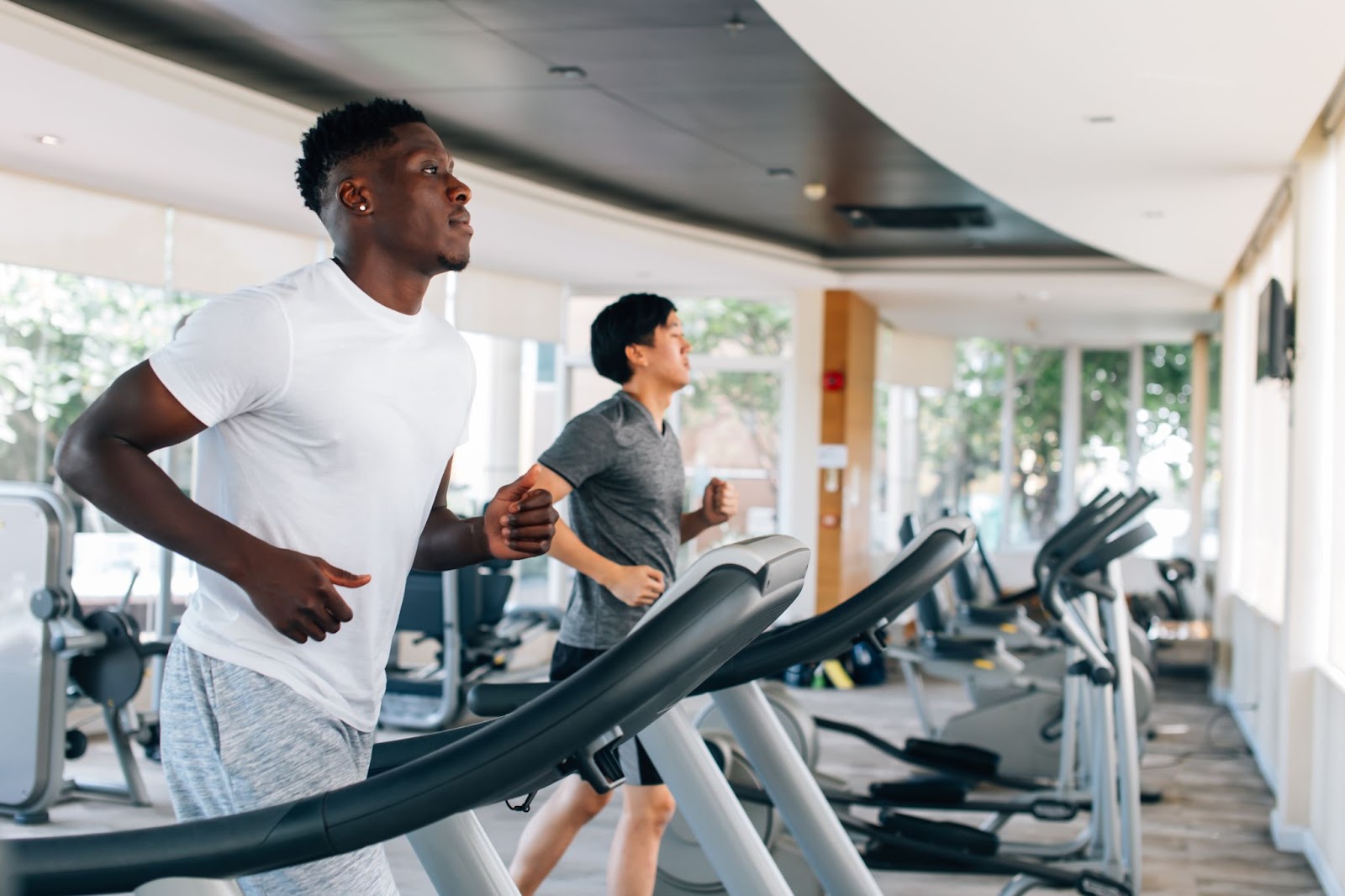 Two men running on treadmills in a modern gym