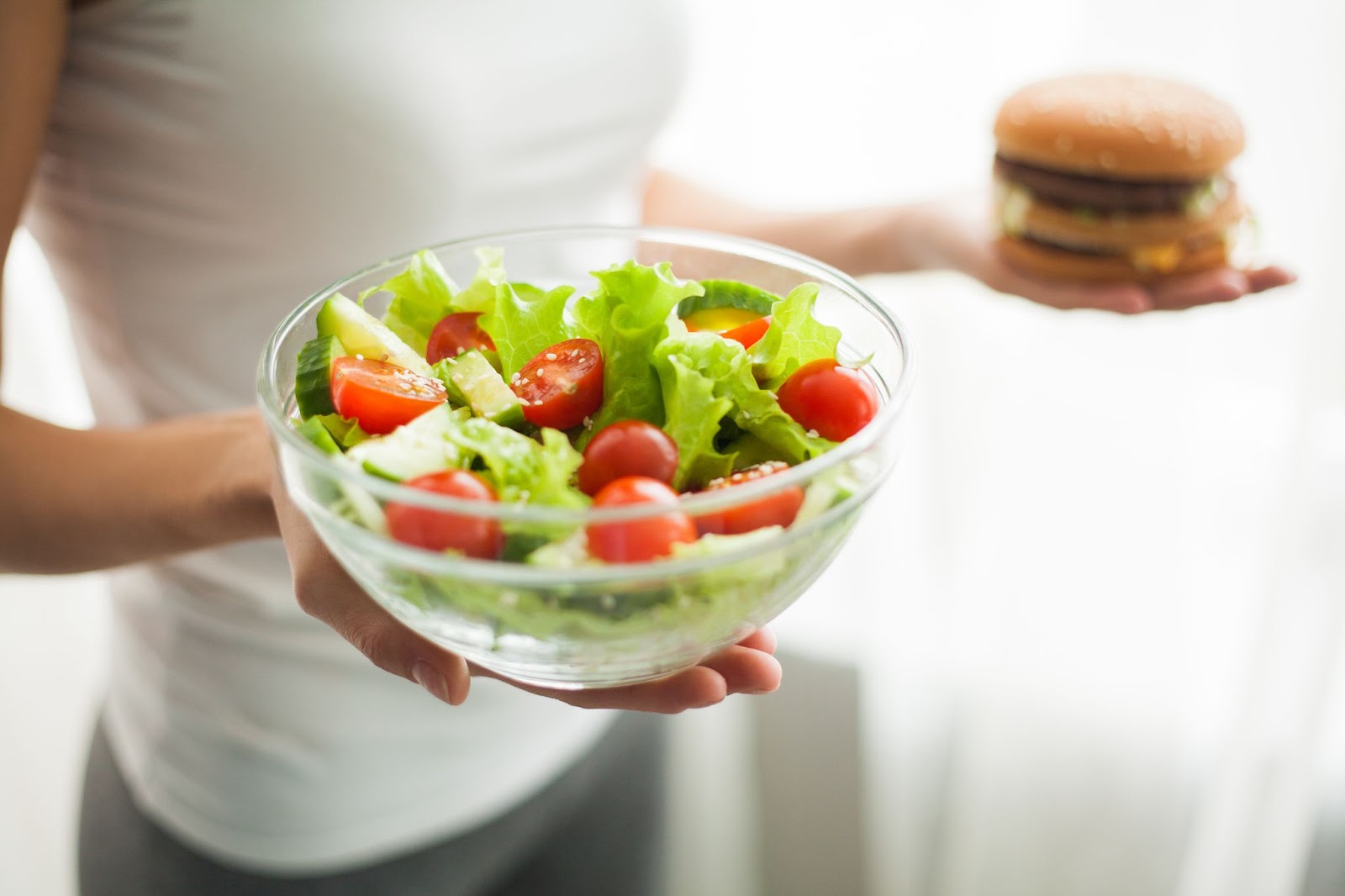 person holding salad and hamburger