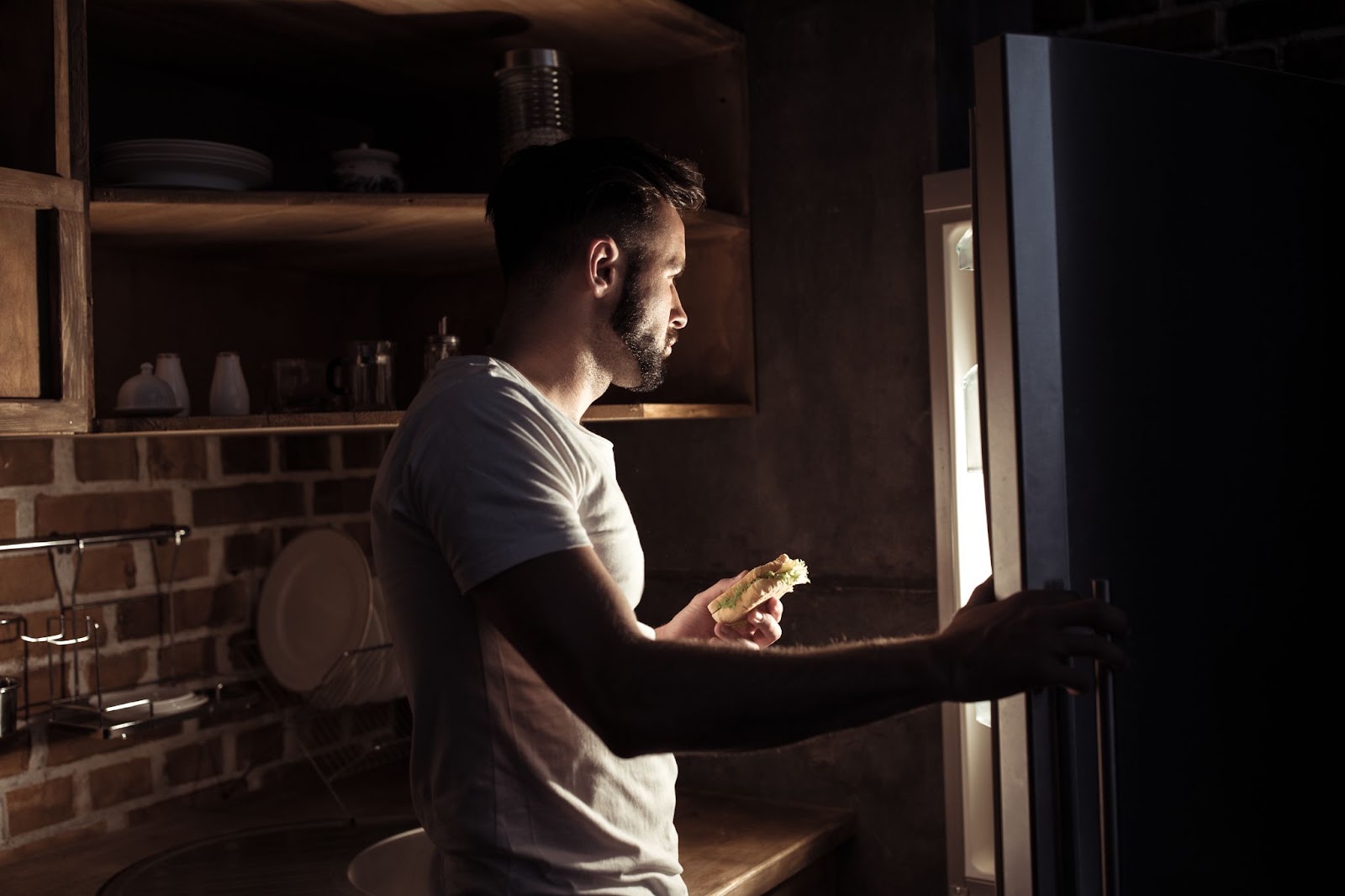 Man opening the refrigerator at home at night