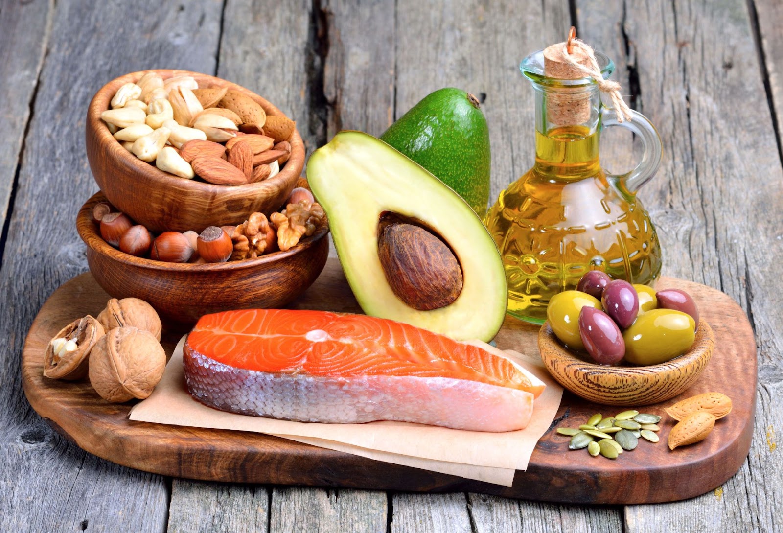 Wooden Board with foods high in healthy fats- salmon, avocado, olives, nuts
