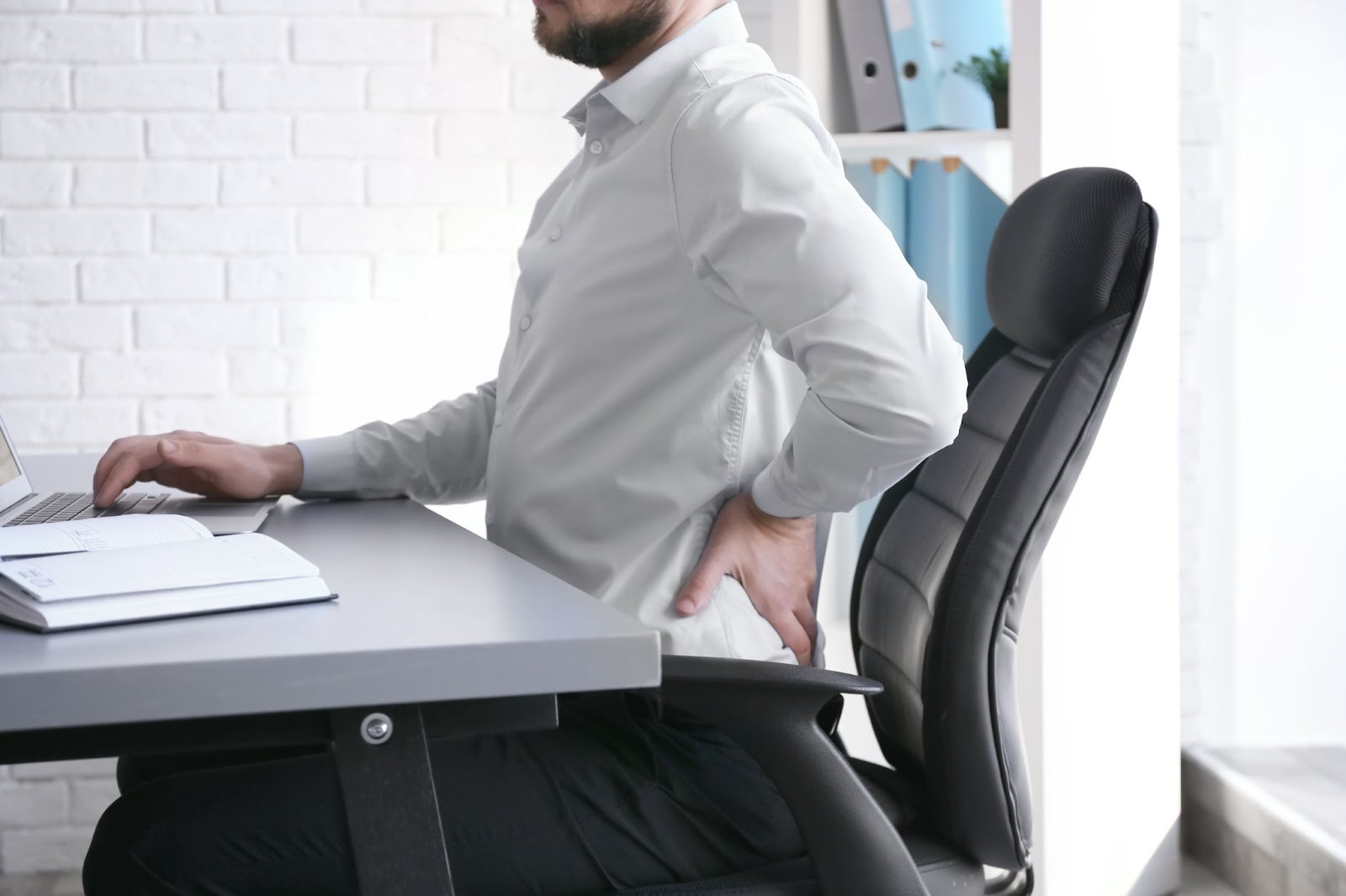 A man at a desk with back pain