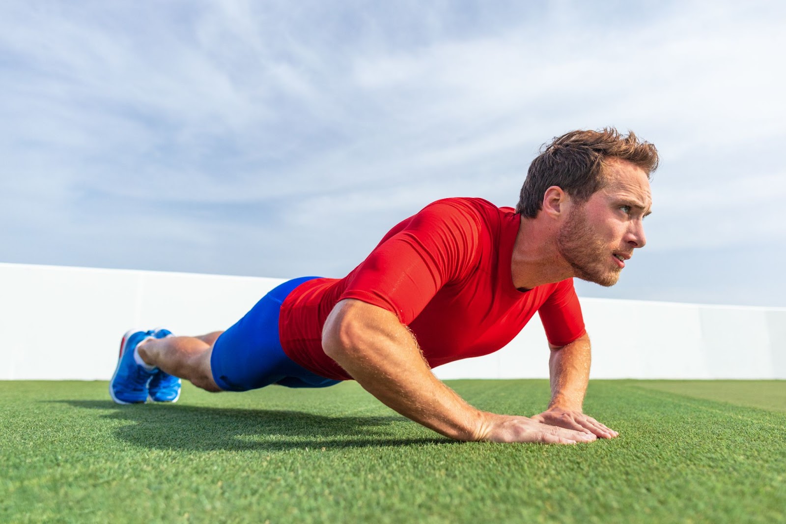 Man performing a tricep push up on astroturf