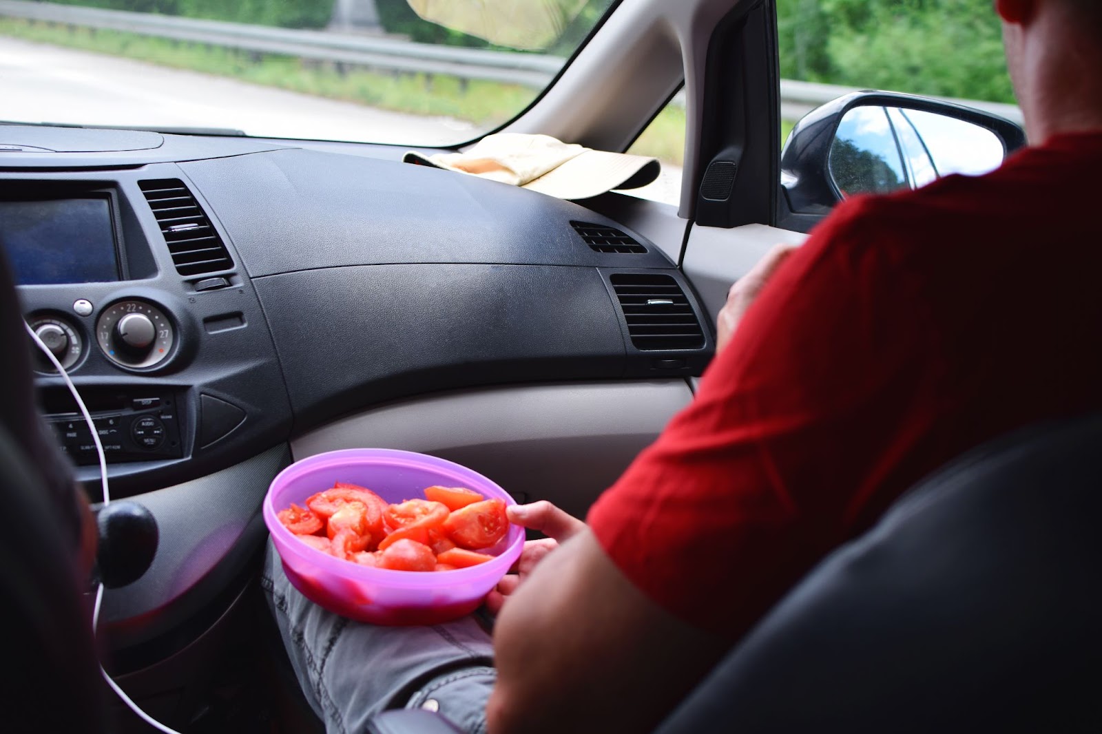 Person eating healthy tomatoes on a road trip