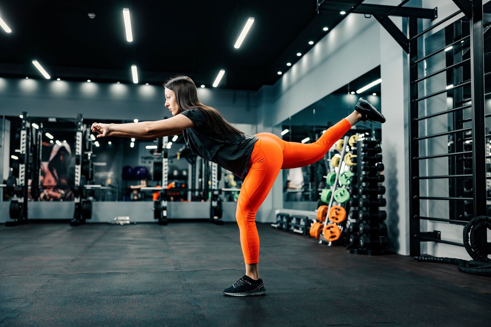 Woman performing single leg balance reach in a gym