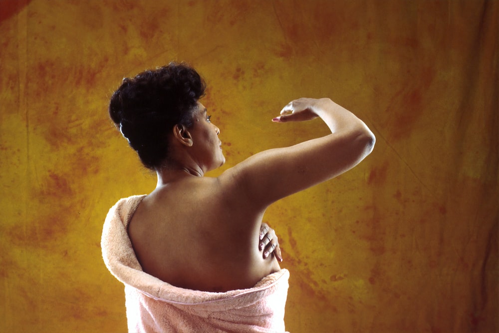 African American woman in a towel checking for breast cancer