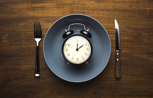 An alarm clock placed on a plate, with a knife and fork on either side