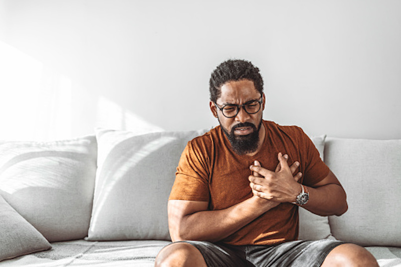 Younger black man, holding his chest and looking sickly