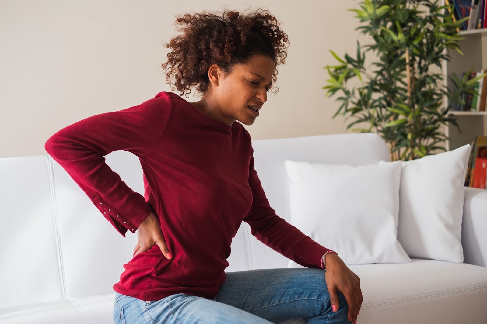 Young woman experiencing back pain at home