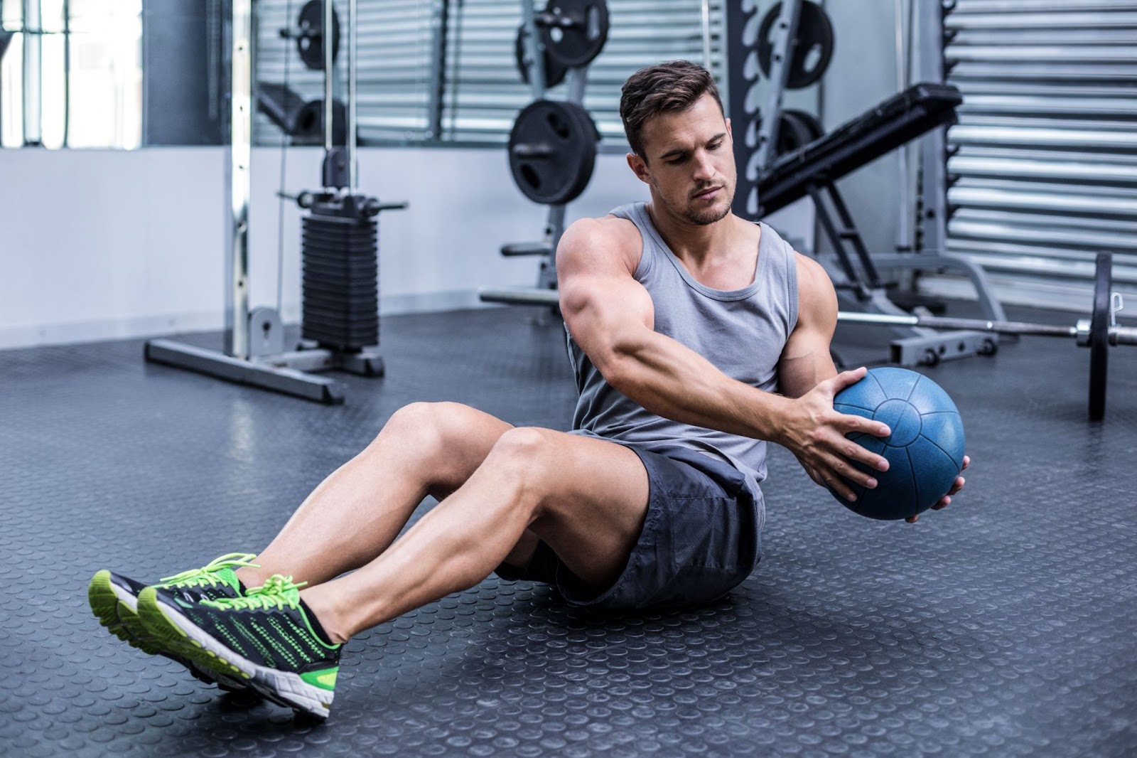 Man performing russian twist with a heavy medicine ball in an industrial gym