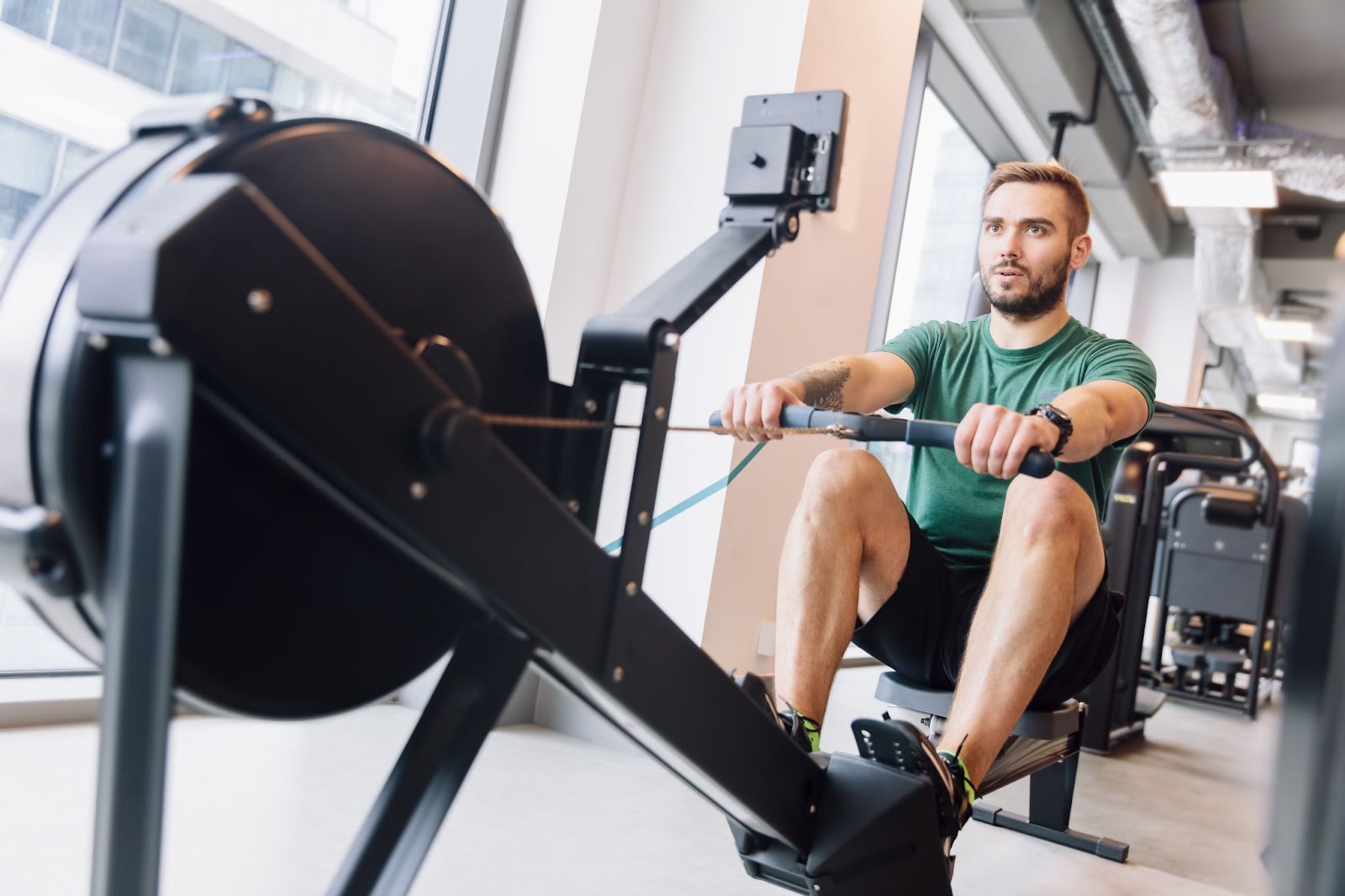 Fit man working out on a rowing machine in a fitness studio