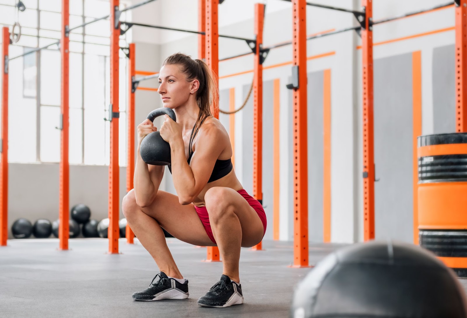 Fit young woman performing a goblet squat with a kettlebell