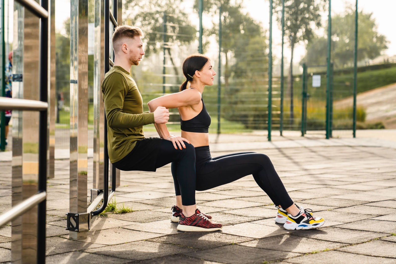 Man doing a wall-sit, with his partner doing a tricep dip using his legs for support