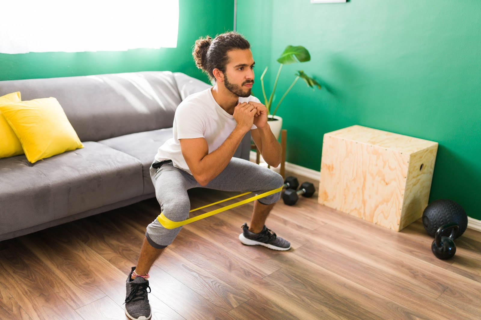 Man with ponytail doing a step-out squat with a resistance band