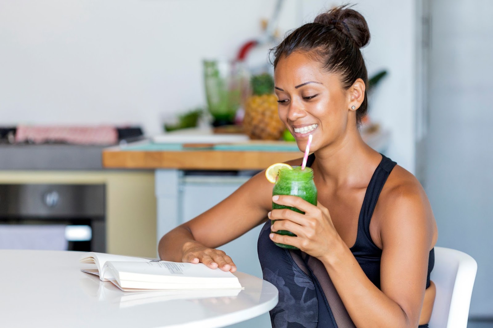 Woman reading a book on Intuitive Eating while sipping a smoothie