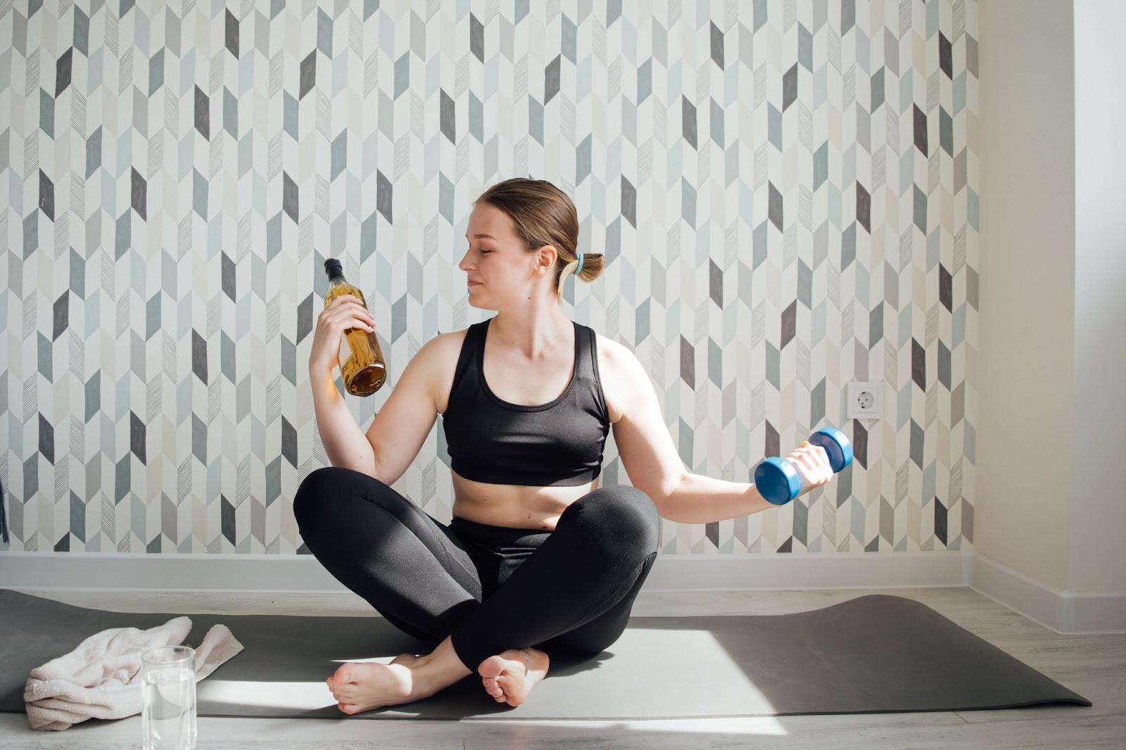 Fit woman dressed in exercise gear deciding to drink alcohol or work out