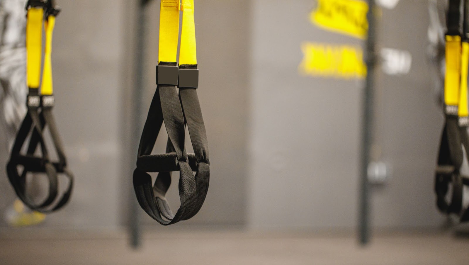 3 pairs of hanging TRX suspension straps in a gray gym