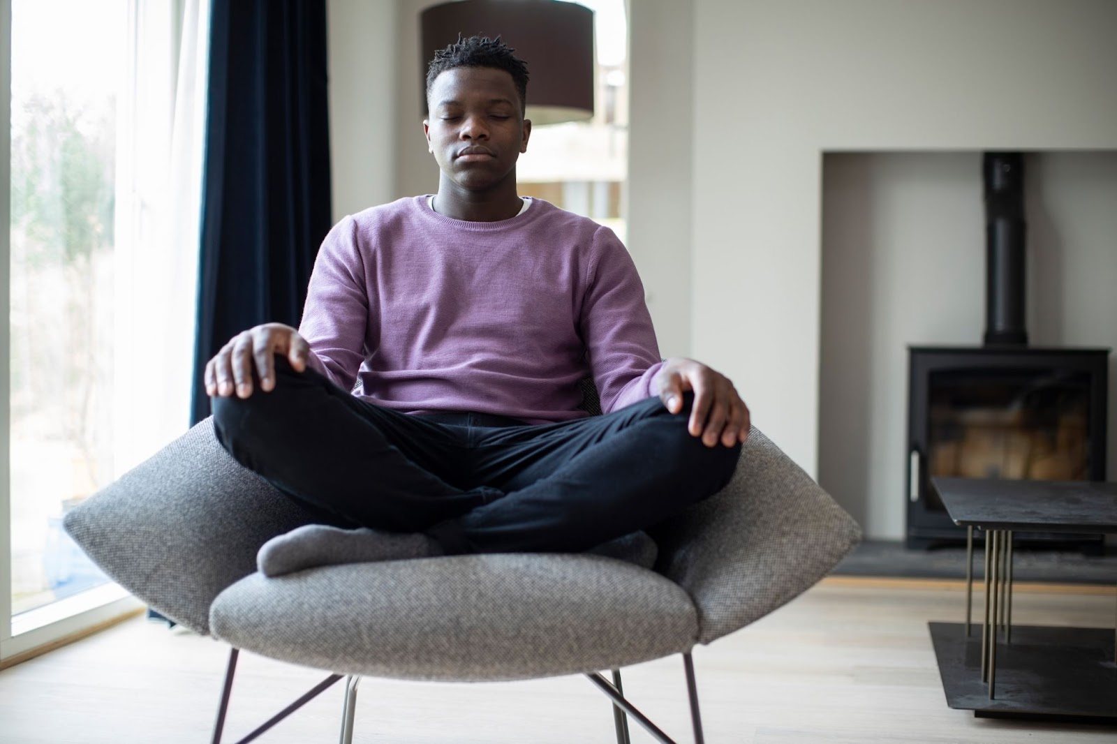 Young man in a purple shirt meditating in a chair