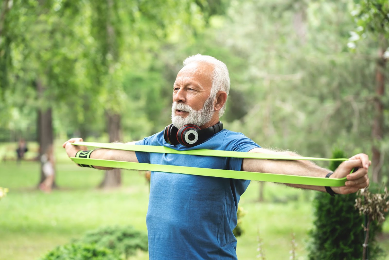 Older man stretching with a resistance band outside