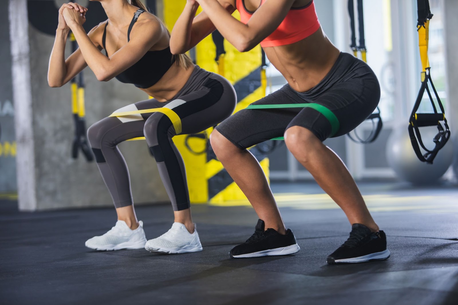 Two women working out next to each other with resistance bands
