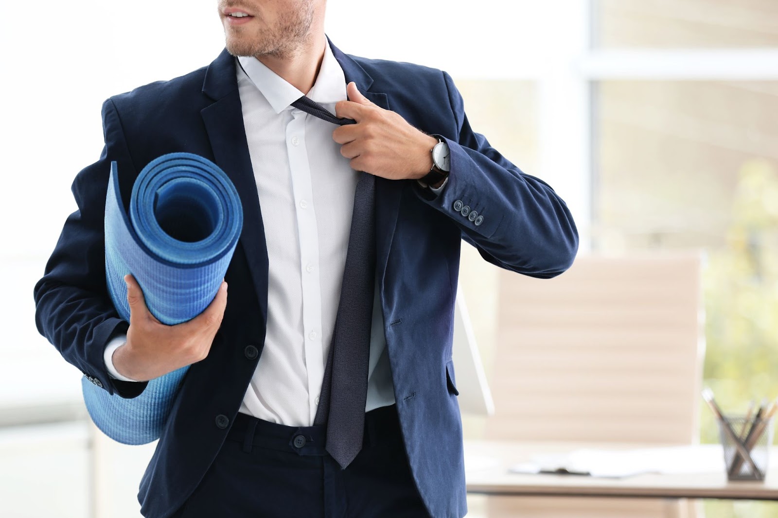 Businessman in a suit, grabbing a yoga towel in his office