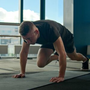 Man in an empty fitness studio performing Mountain Climbers