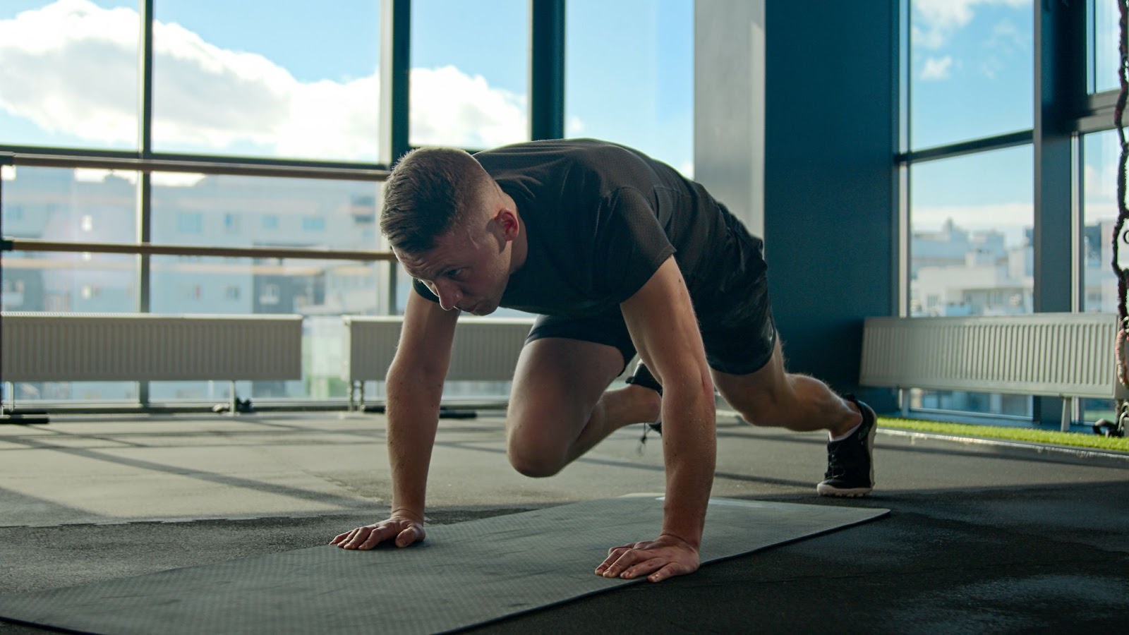 Man in an empty fitness studio performing Mountain Climbers