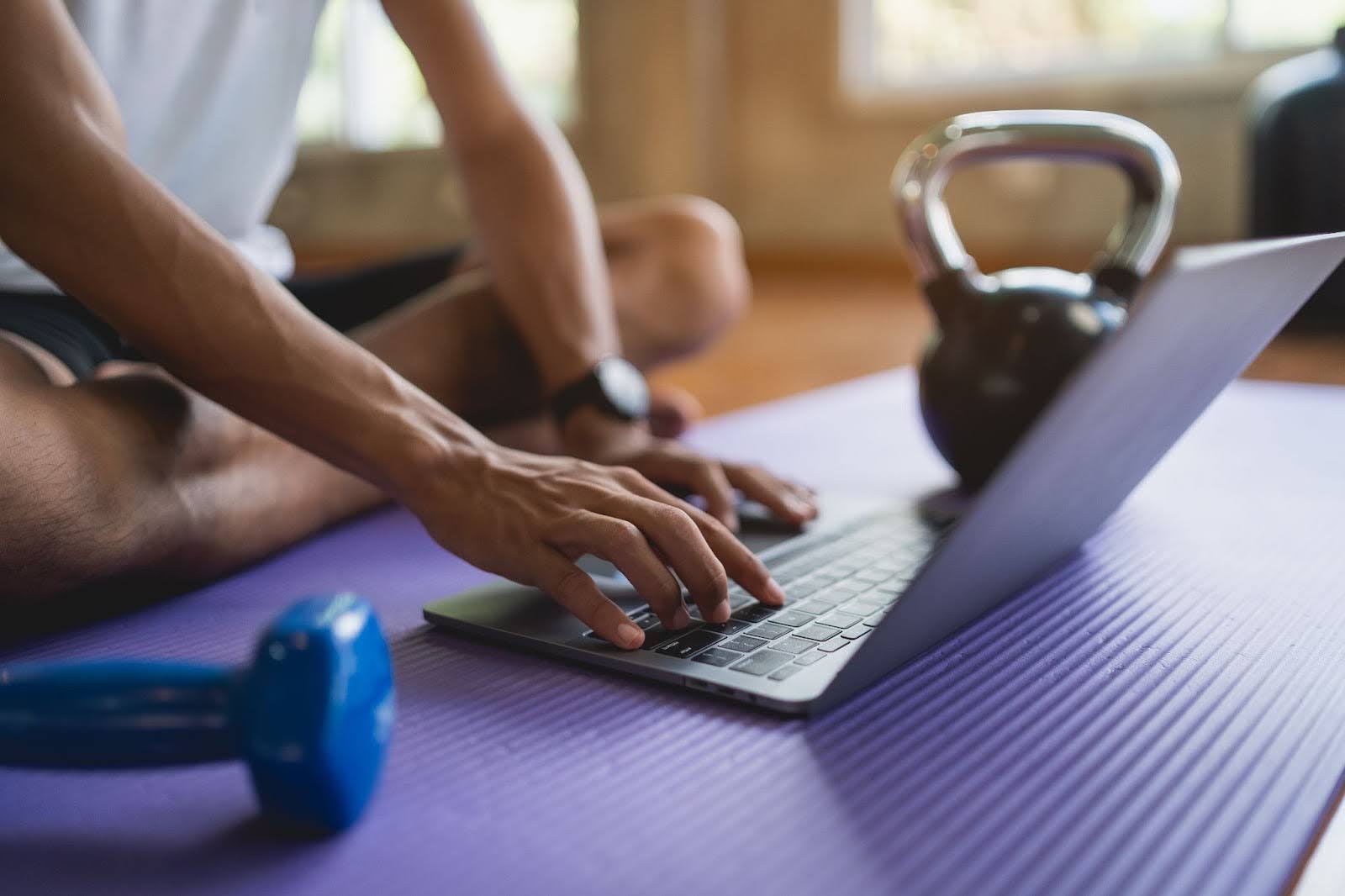 closeup of fit man, taking a yoga class next to a laptop