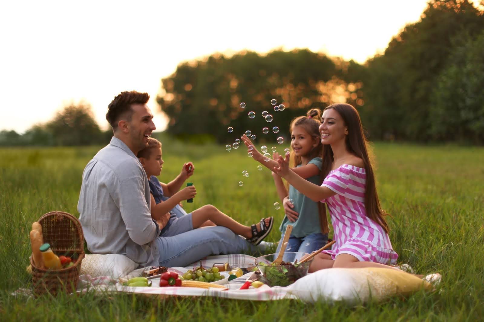 Family taking a Valentine’s Day picnic in a park at sunset