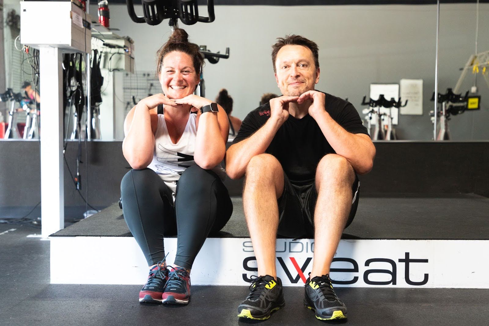 Studio SWEAT onDemand trainers smiling, sitting next to each other