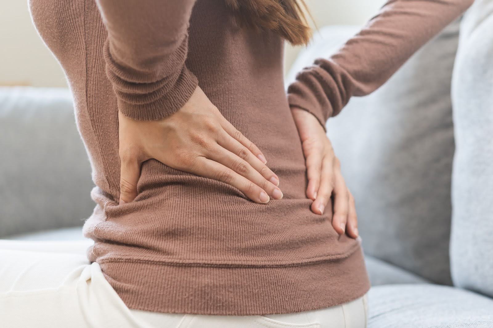 Woman holding her lower back, experiencing pain in her psoas region