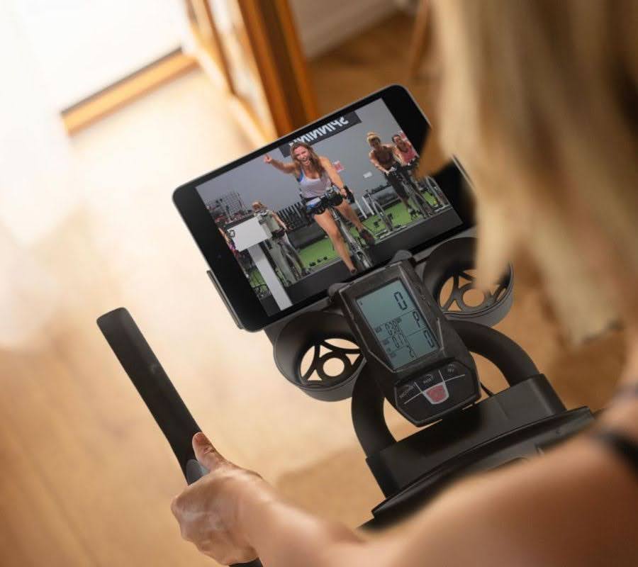 Woman taking a cycling class through her tablet, at home