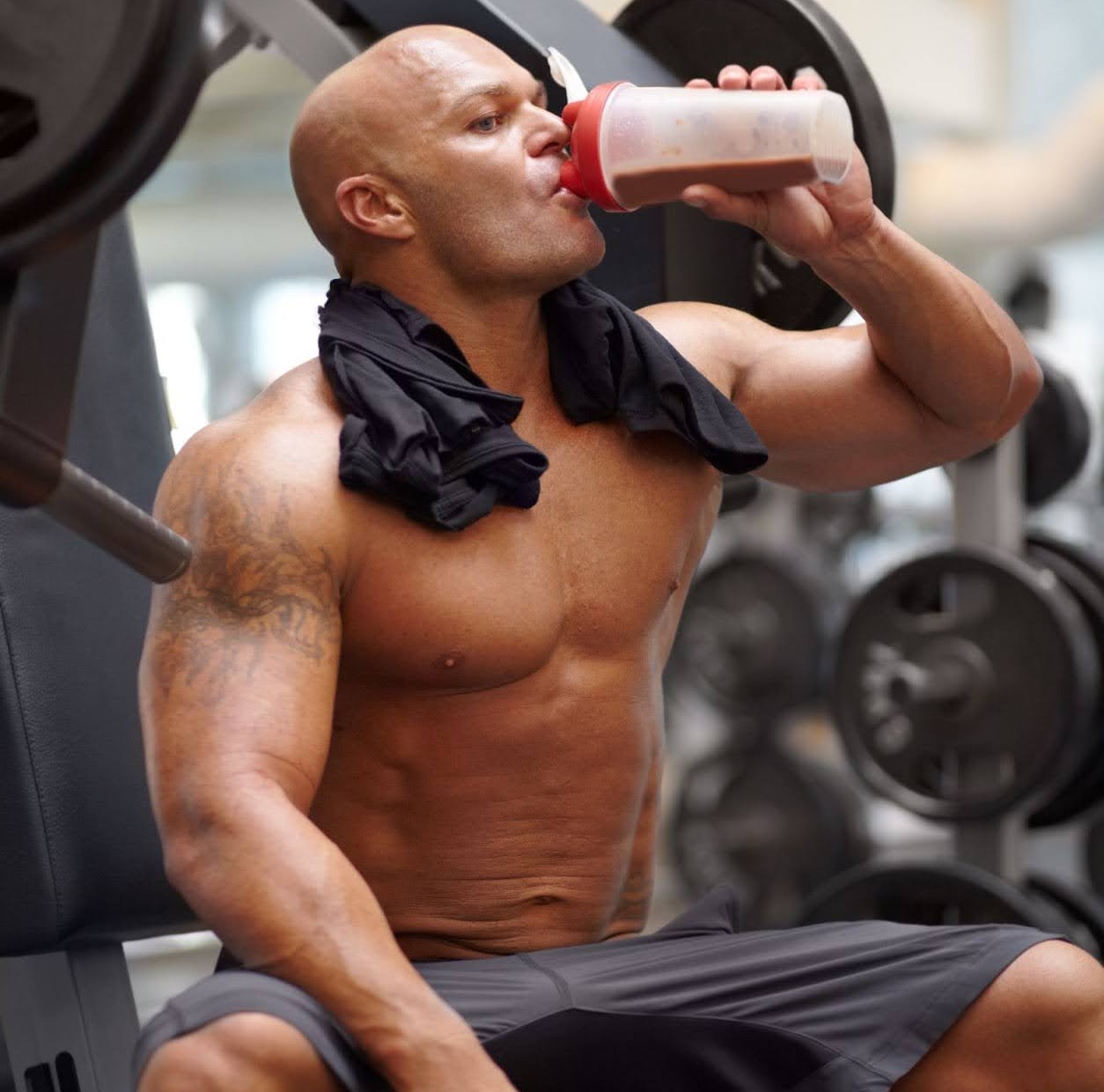 Muscular man drinking a protein smoothie at the gym
