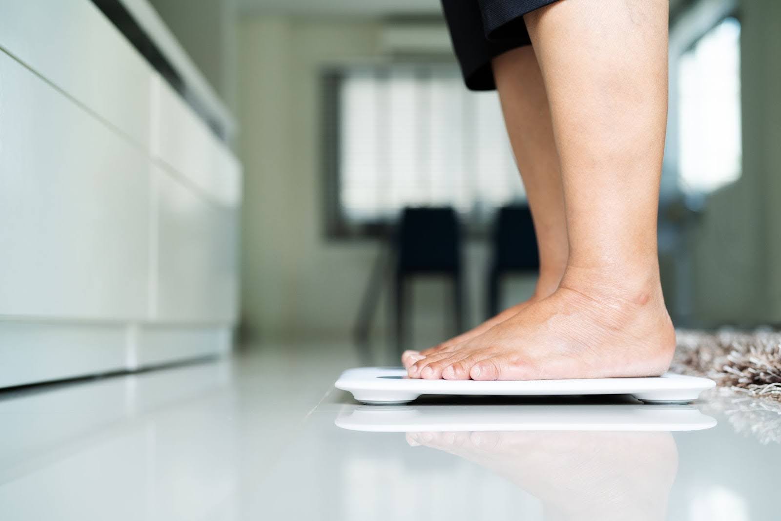 Closeup of a person’s feet, standing on a scale in their bathroom