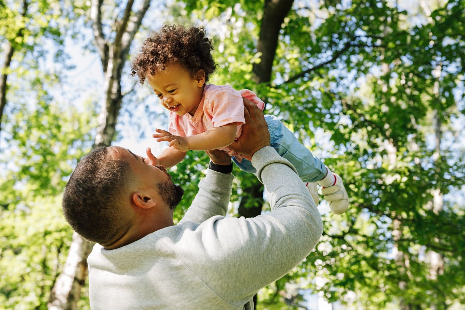Father lifting his toddler up in the air in a forest