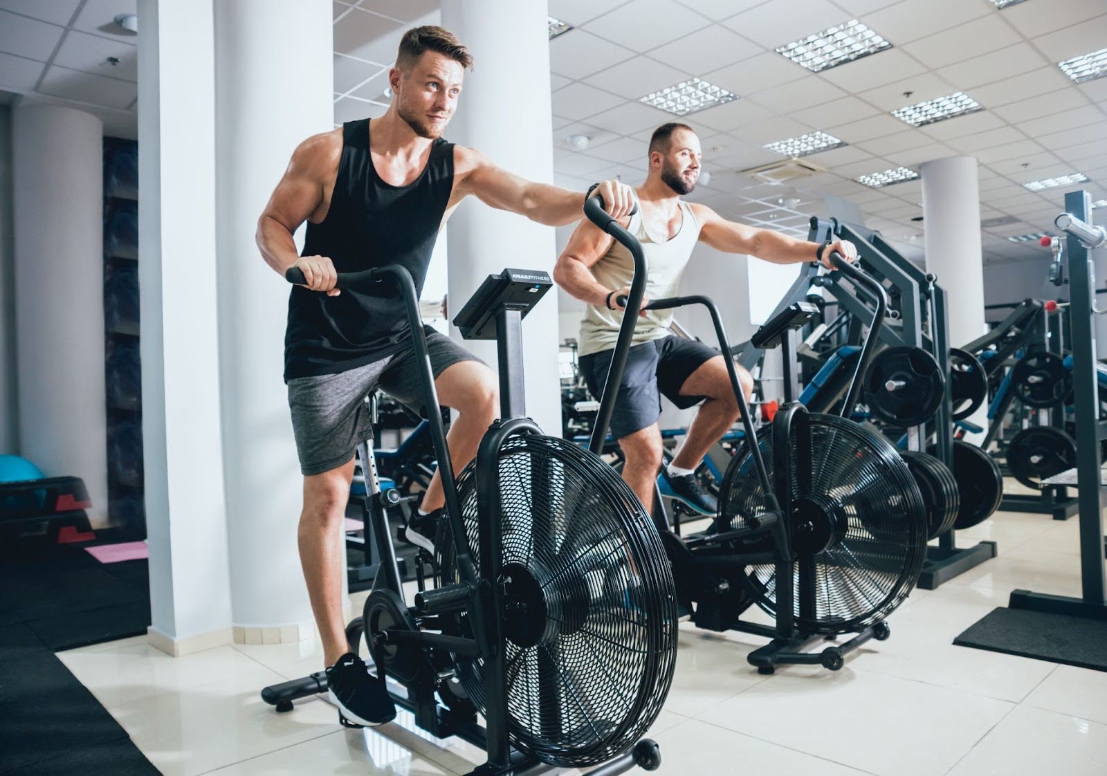 Two men riding air bikes in a fitness studio