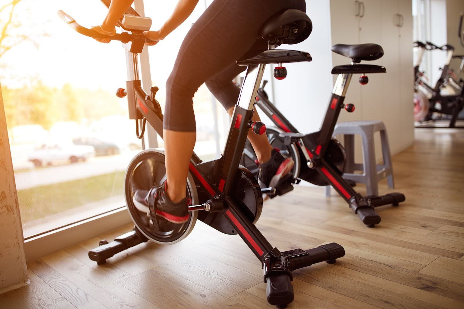 Woman on an indoor cycling bike in a small fitness space