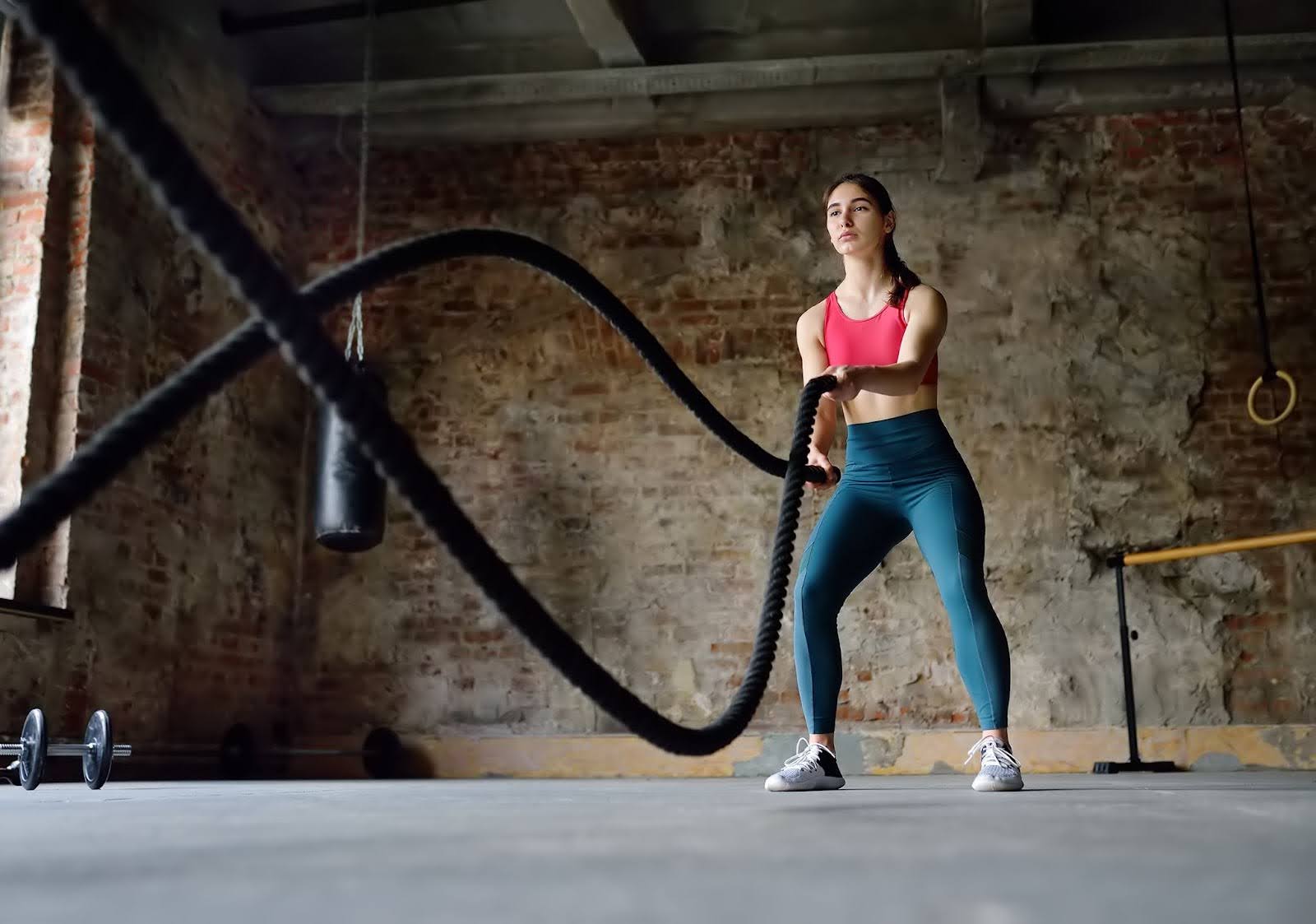 Fit young woman in a gym using battle ropes