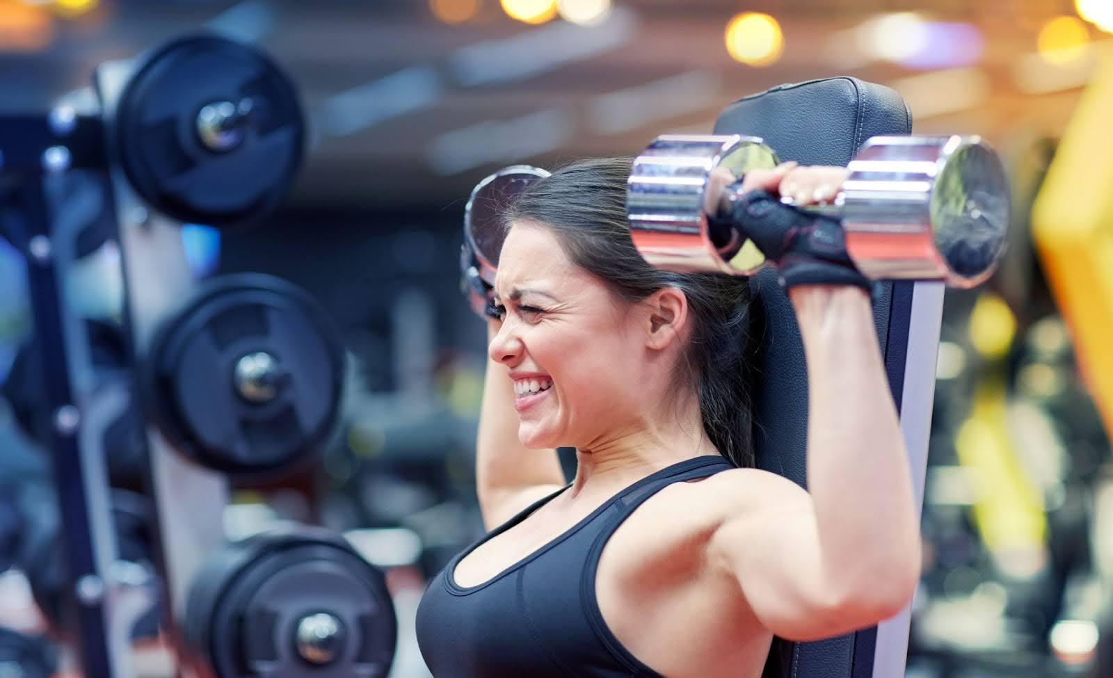 Woman struggling to lift her last few reps in a shoulder press