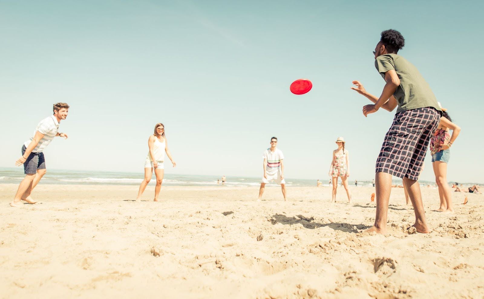 Group of people playing a game of frisbee at the beach