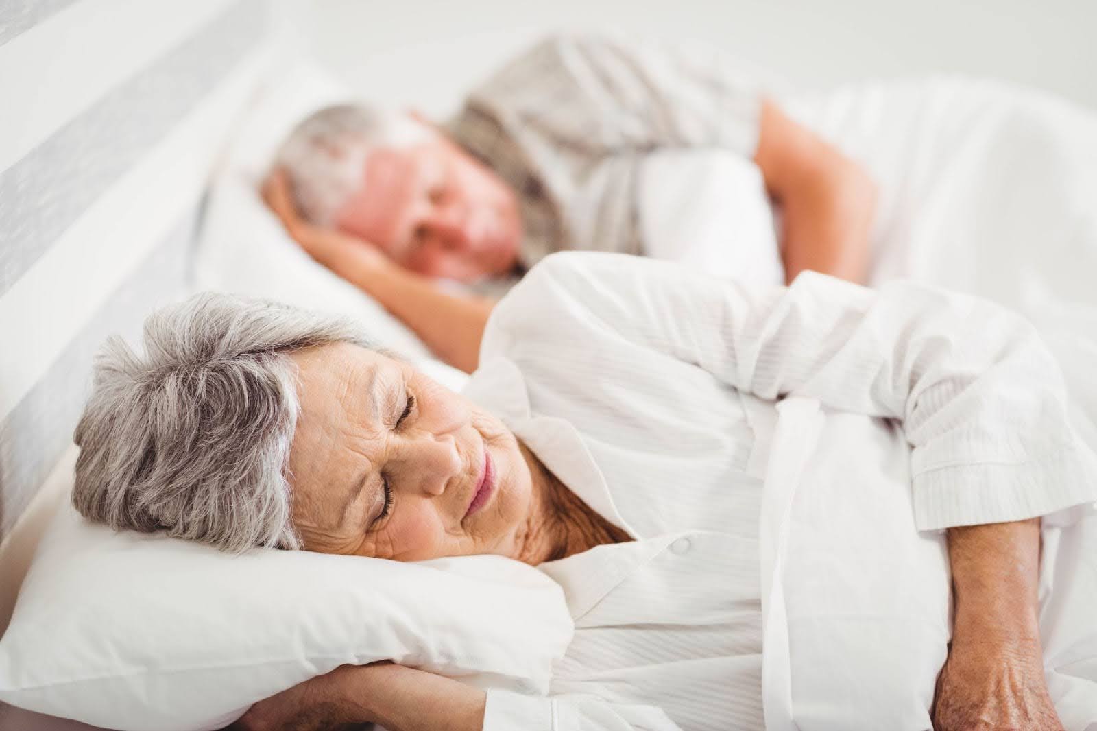 Older man and woman sleeping comfortably in a bed