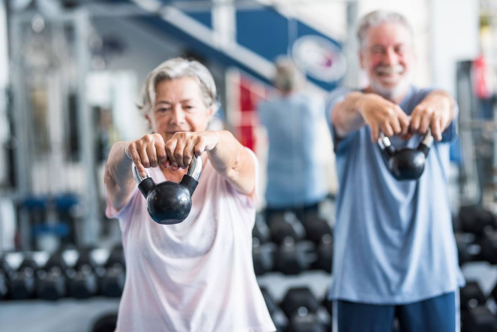 Senior couple going to the gym and weight training with kettlebells